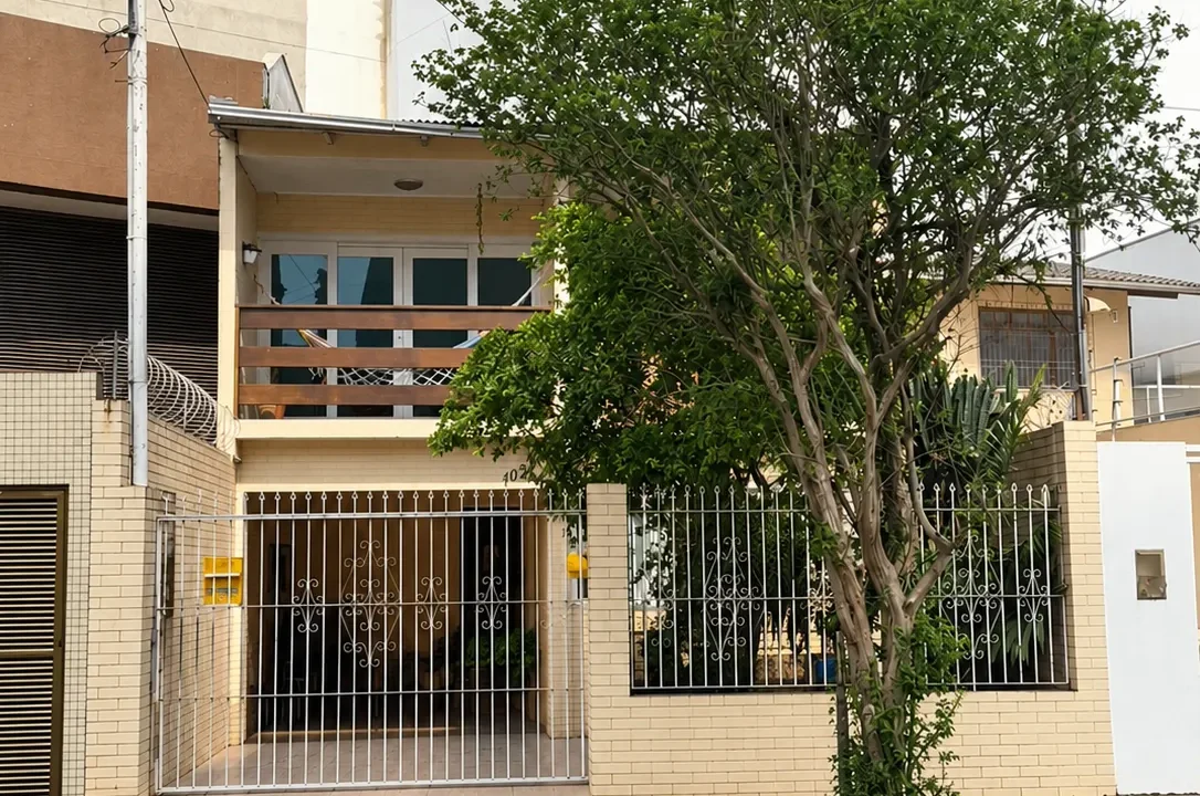 Fachada urbana ensolarada com árvore e portão