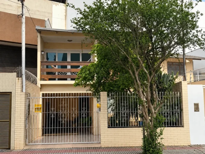 Fachada urbana ensolarada com arvore e portao